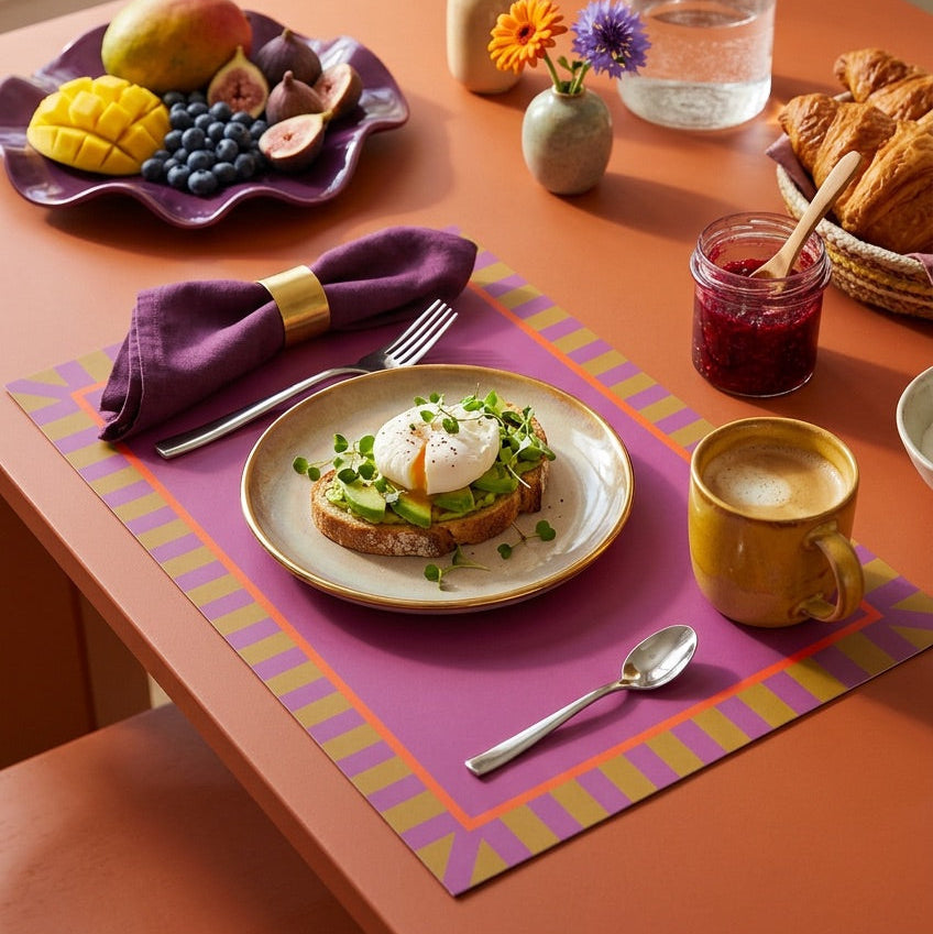 Breakfast setting with avocado toast, poached egg, and coffee on a colorful placemat.