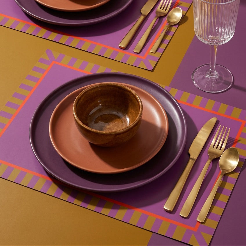 Dinner setting with brown bowls and plates on a colorful paper placemat.