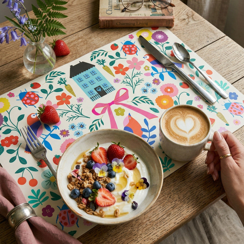 Colorful floral paper placemats styled on a wood table with yogurt and coffee. 