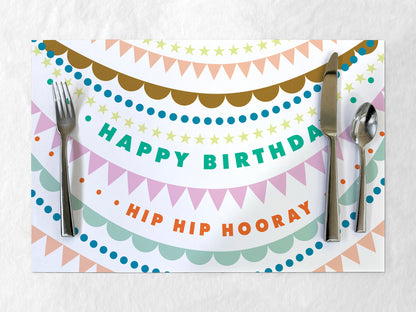 Colorful 'Happy Birthday Hip Hip Hooray' paper placemat with cutlery on a white background