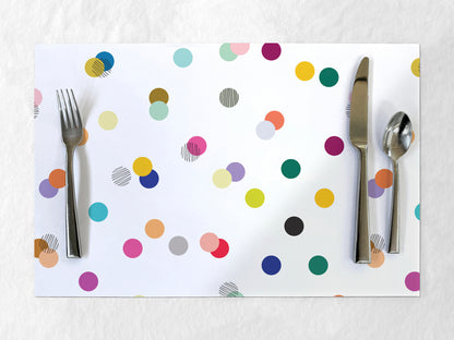 Colorful polka dot paper placemat with cutlery on a white background
