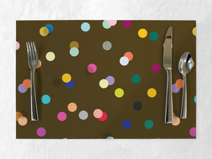 Brown paper placemat with colorful dot pattern and silverware on a white background