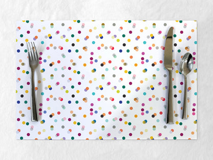 Polka dot paper placemat with cutlery on a white background