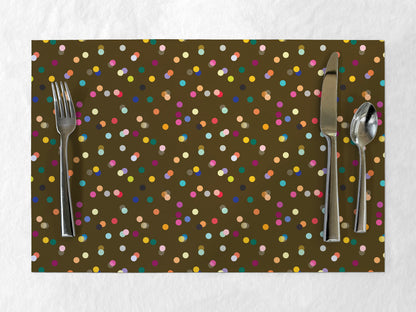 Paper placemat with colorful confetti dot pattern and cutlery on a white background
