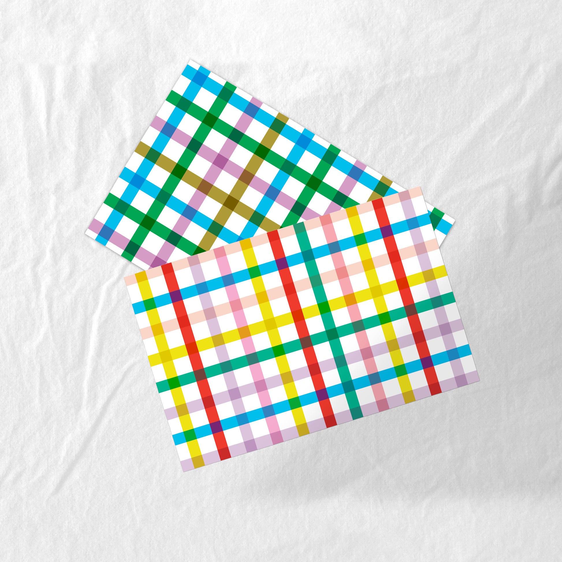 Set of colorful plaid paper placemats on a white fabric background