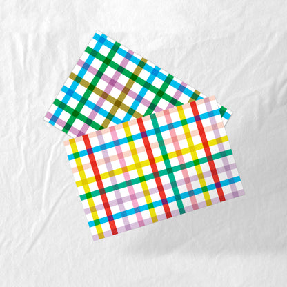 Set of colorful plaid paper placemats on a white fabric background