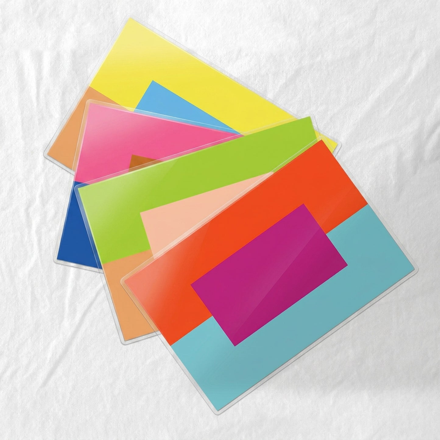 Colorful laminated paper placemats stacked on a textured white surface