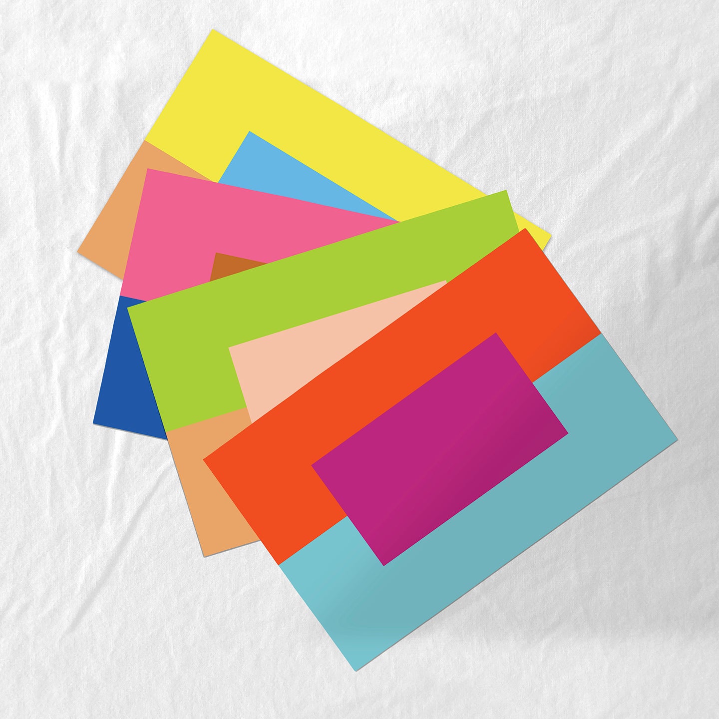 Stack of colorful paper placemats on a white fabric background
