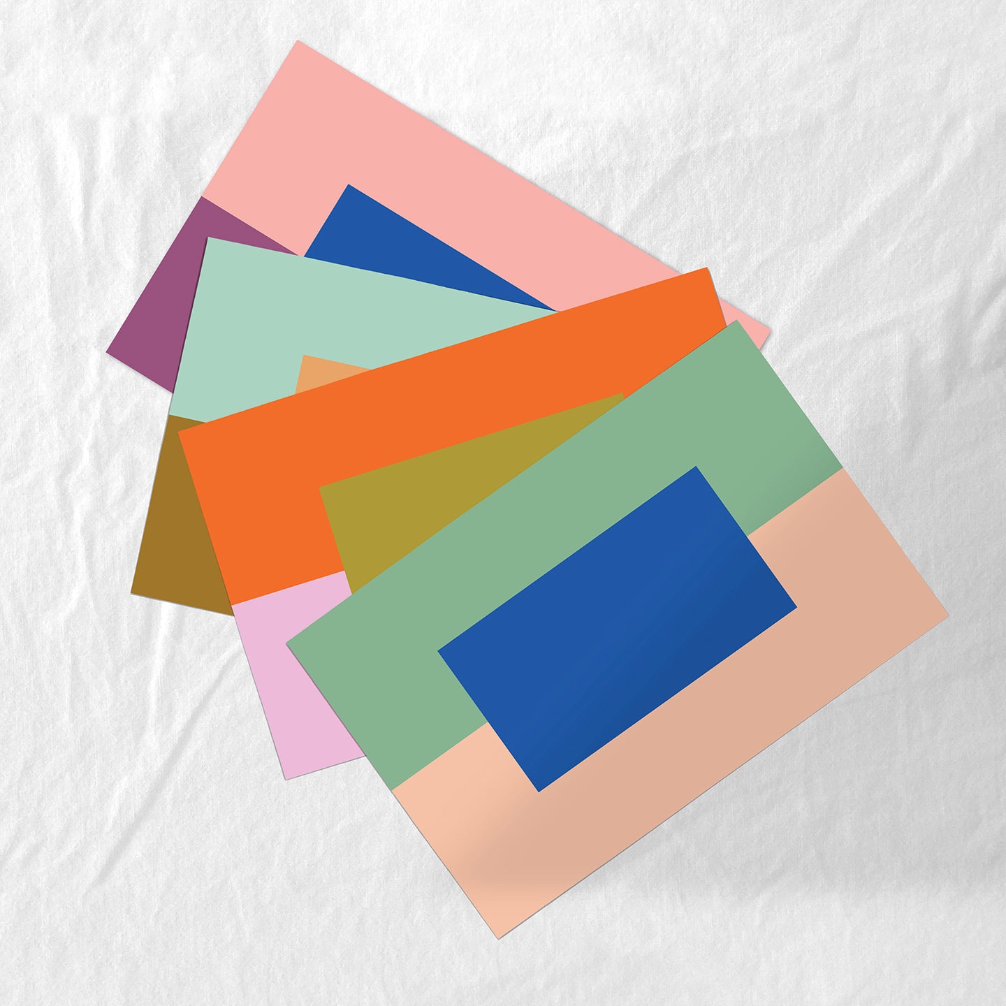 Colorful paper placemats stacked on a white fabric background