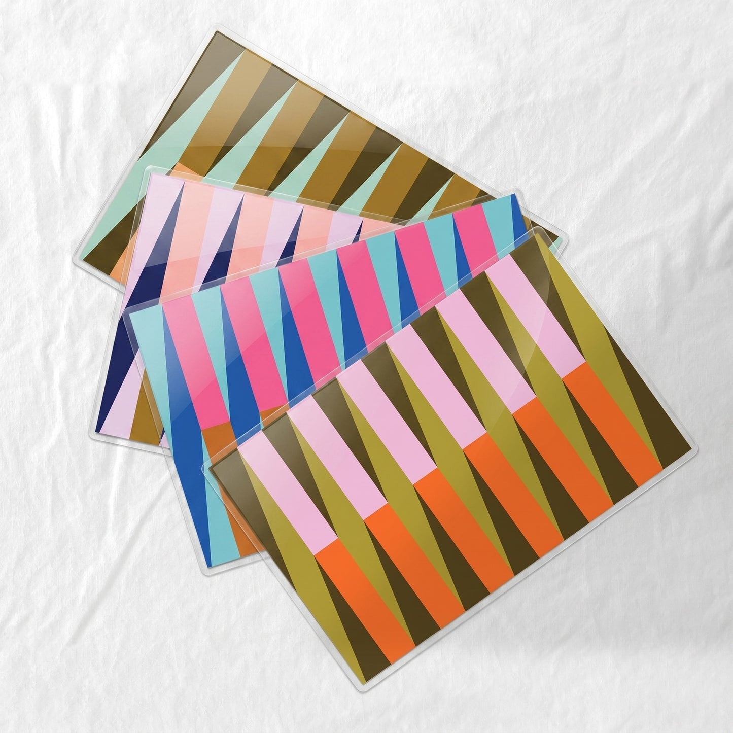 Colorful striped laminated paper placemats on a white fabric background