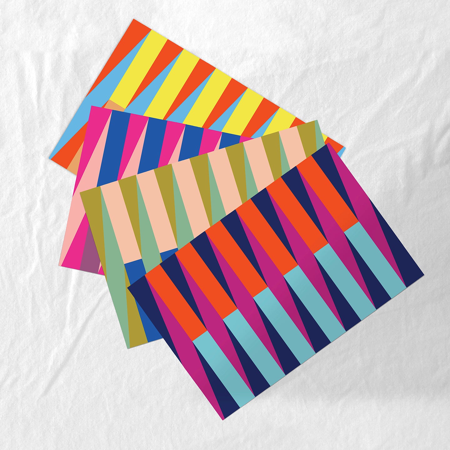 Colorful striped paper placemats on a white fabric background