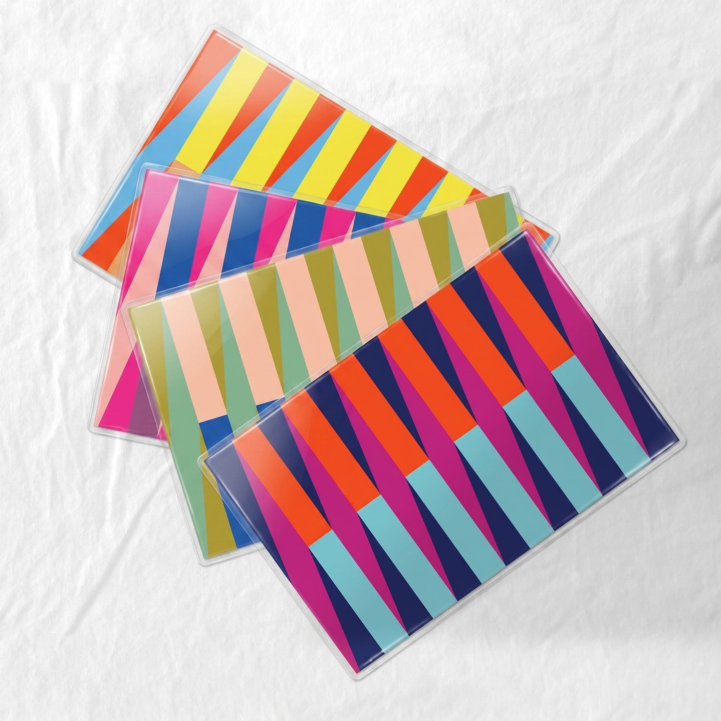 Set of colorful striped laminated paper placemats on a white fabric background