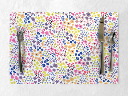 Colorful floral-patterned paper placemat with cutlery on a white background