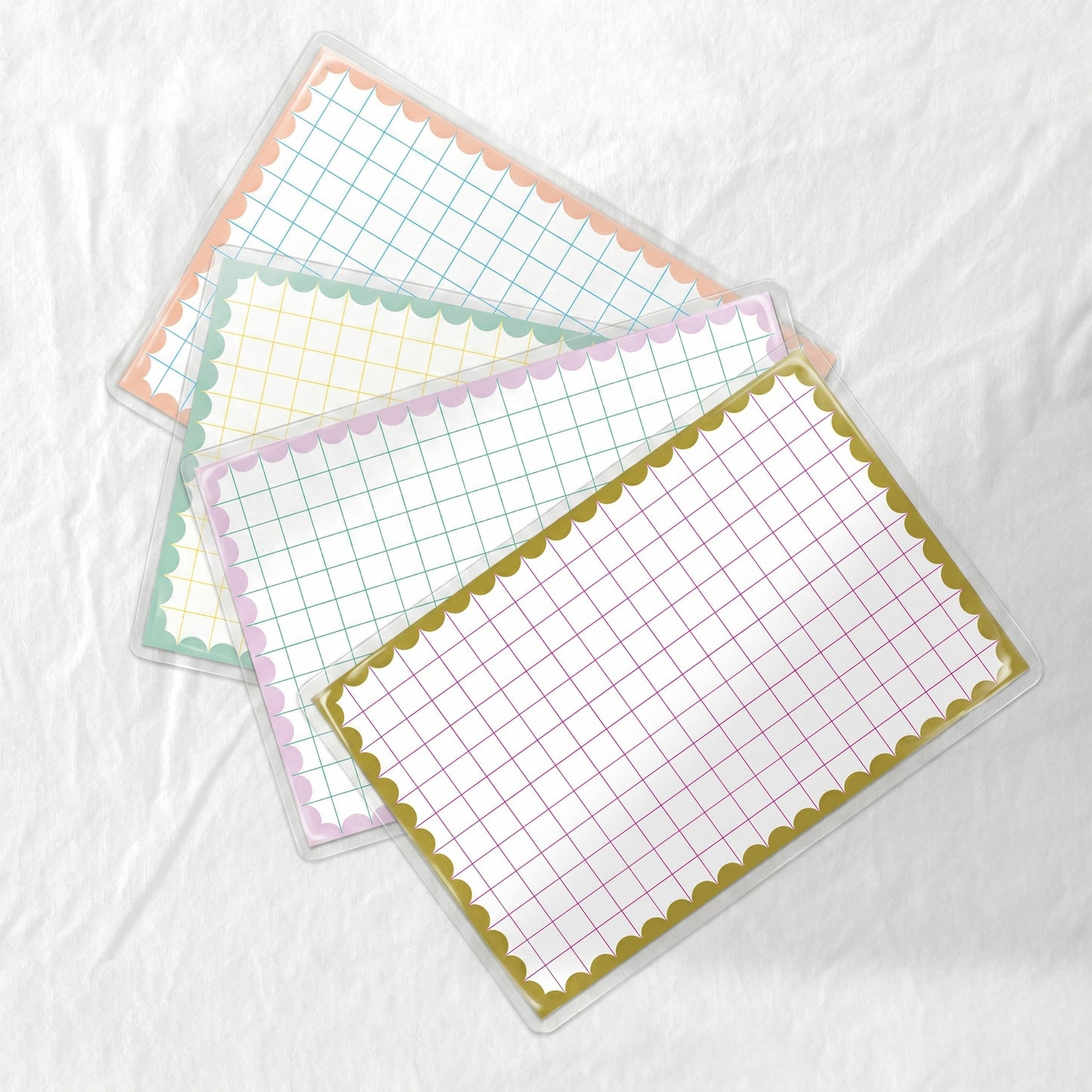 Four grid-lined paper placemats with decorative borders on a white background