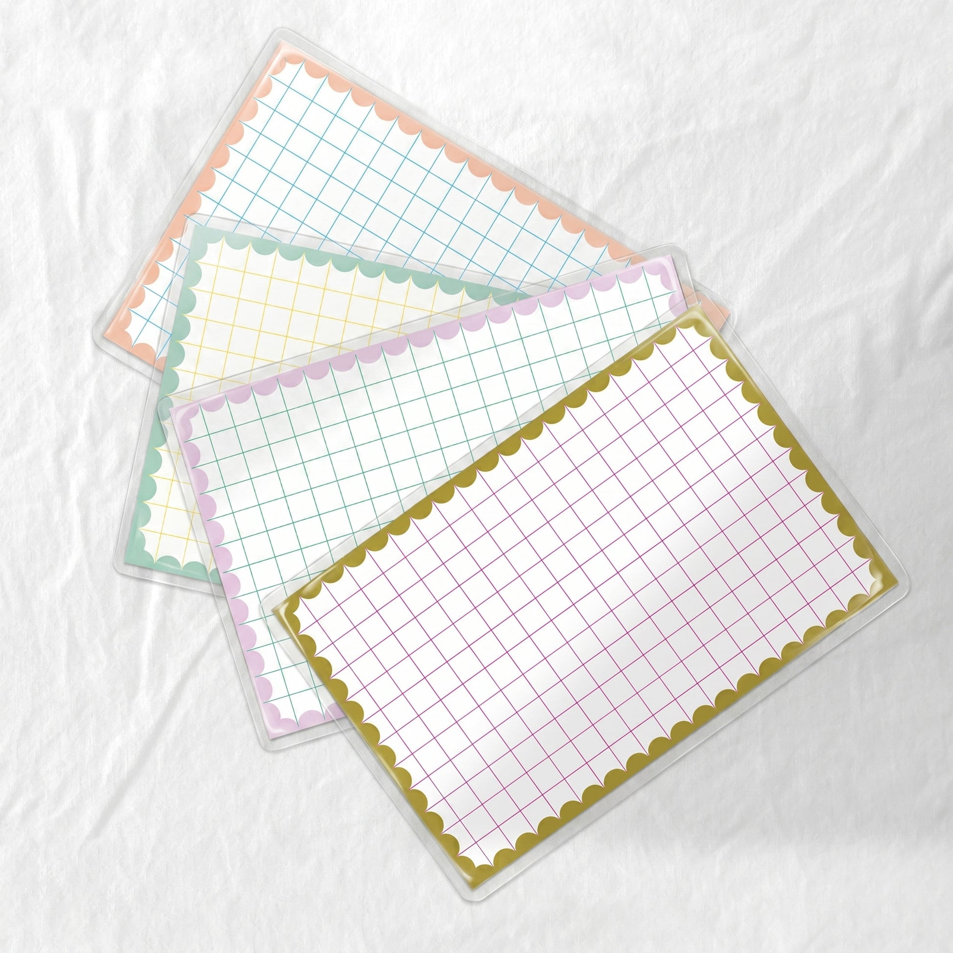 Four grid-lined paper placemats with decorative borders on a white background