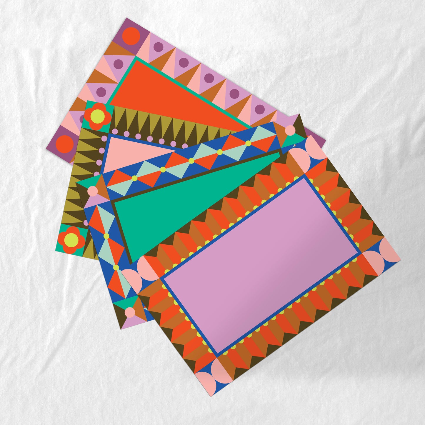 Set of 4 colorful geometric patterned paper placemats on a white background