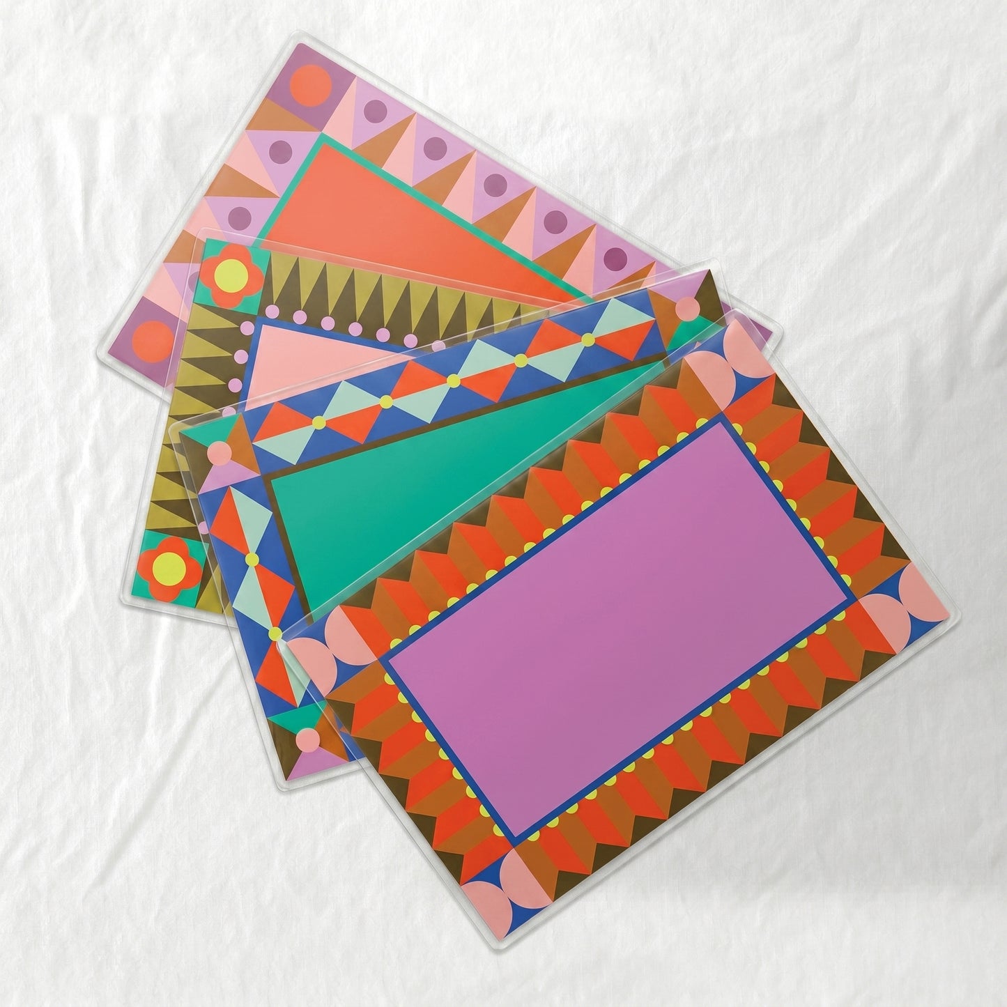 Set of 4 colorful geometric patterned laminated paper placemats on a white background