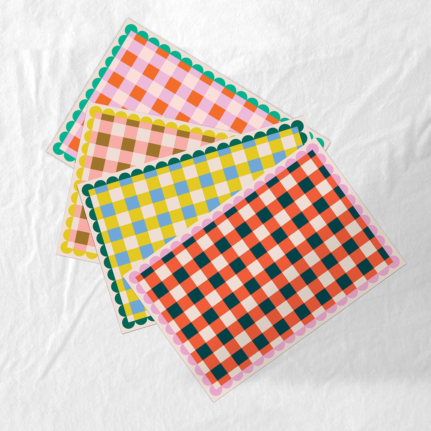 Set of four colorful checkered paper placemats on a white background