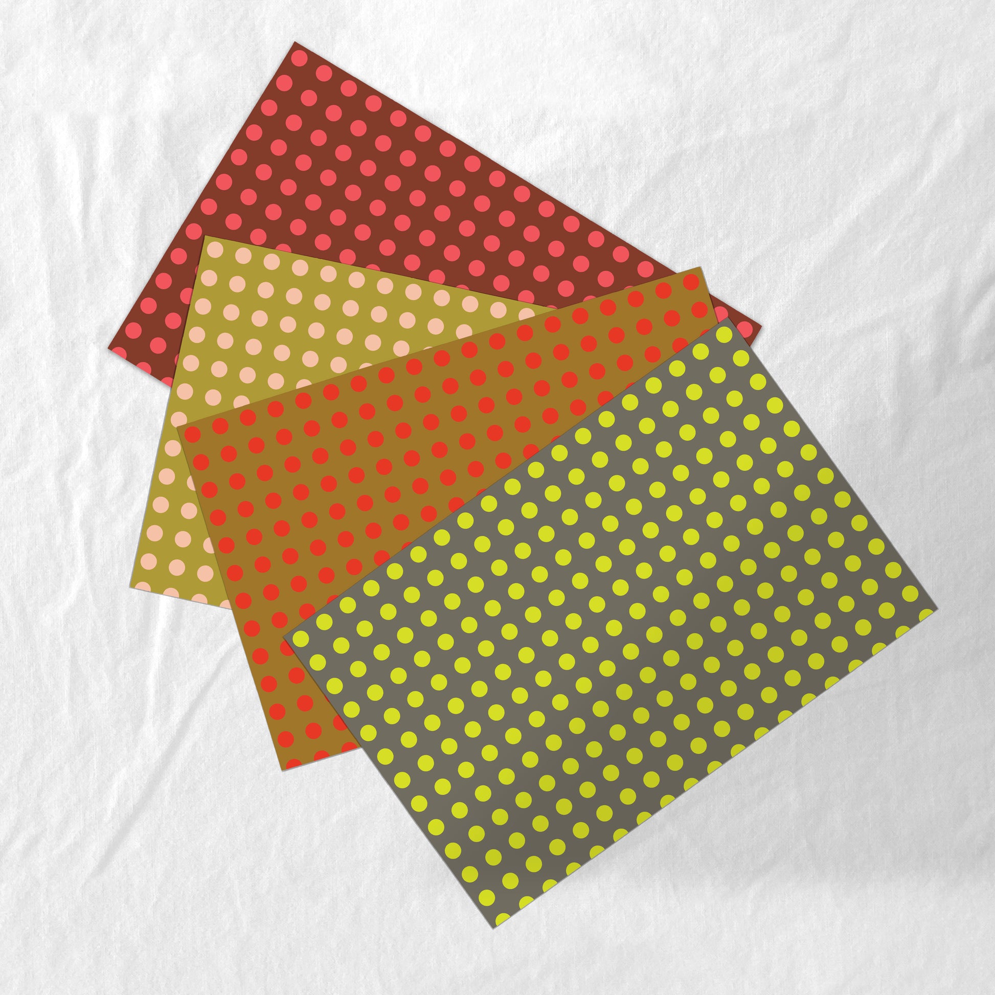 Four sheets of polka dot paper placemats in different colors on a white background