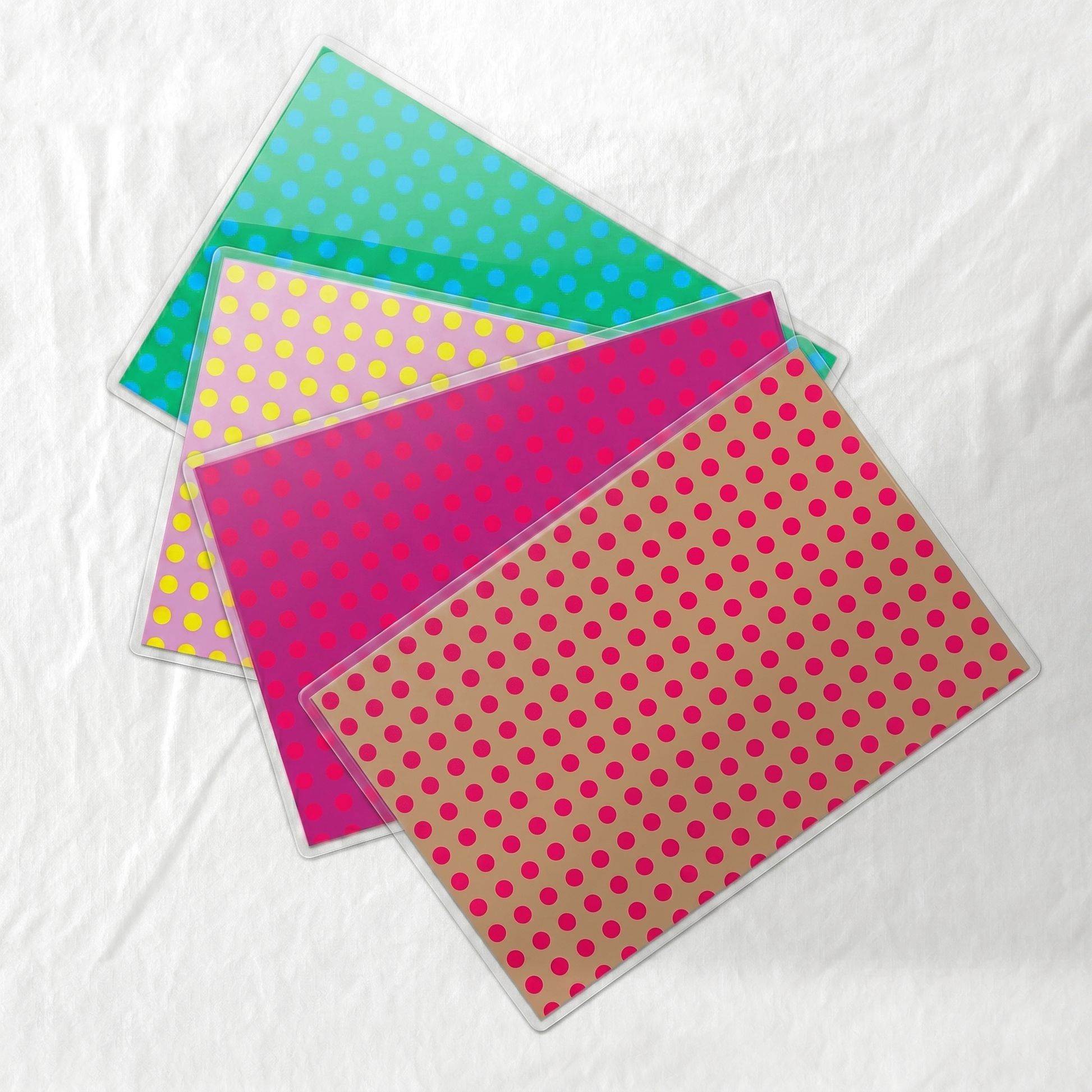 Four colorful polka dot laminated paper placemats on a white background