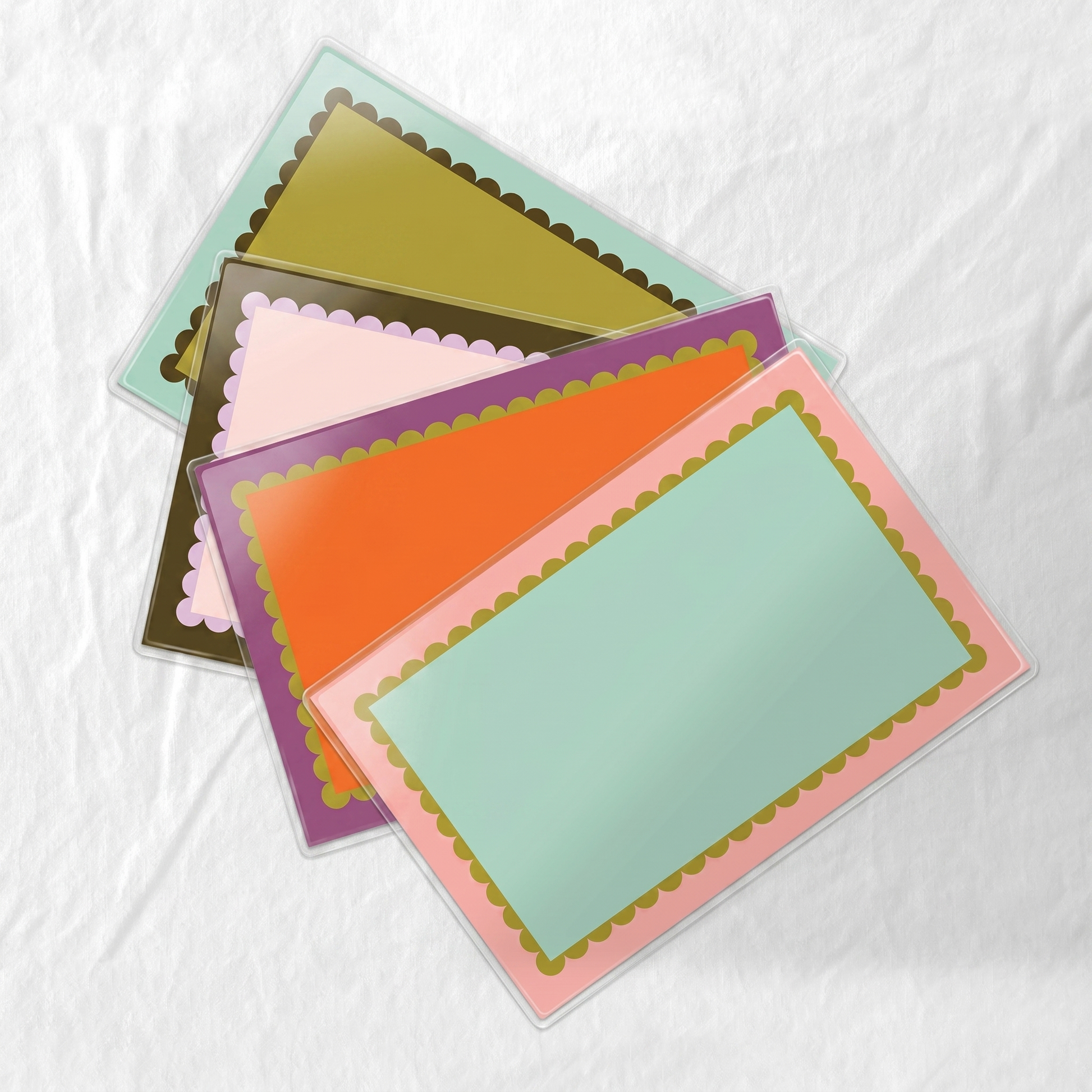 Colorful laminated paper placemat set with scallop frame design. 