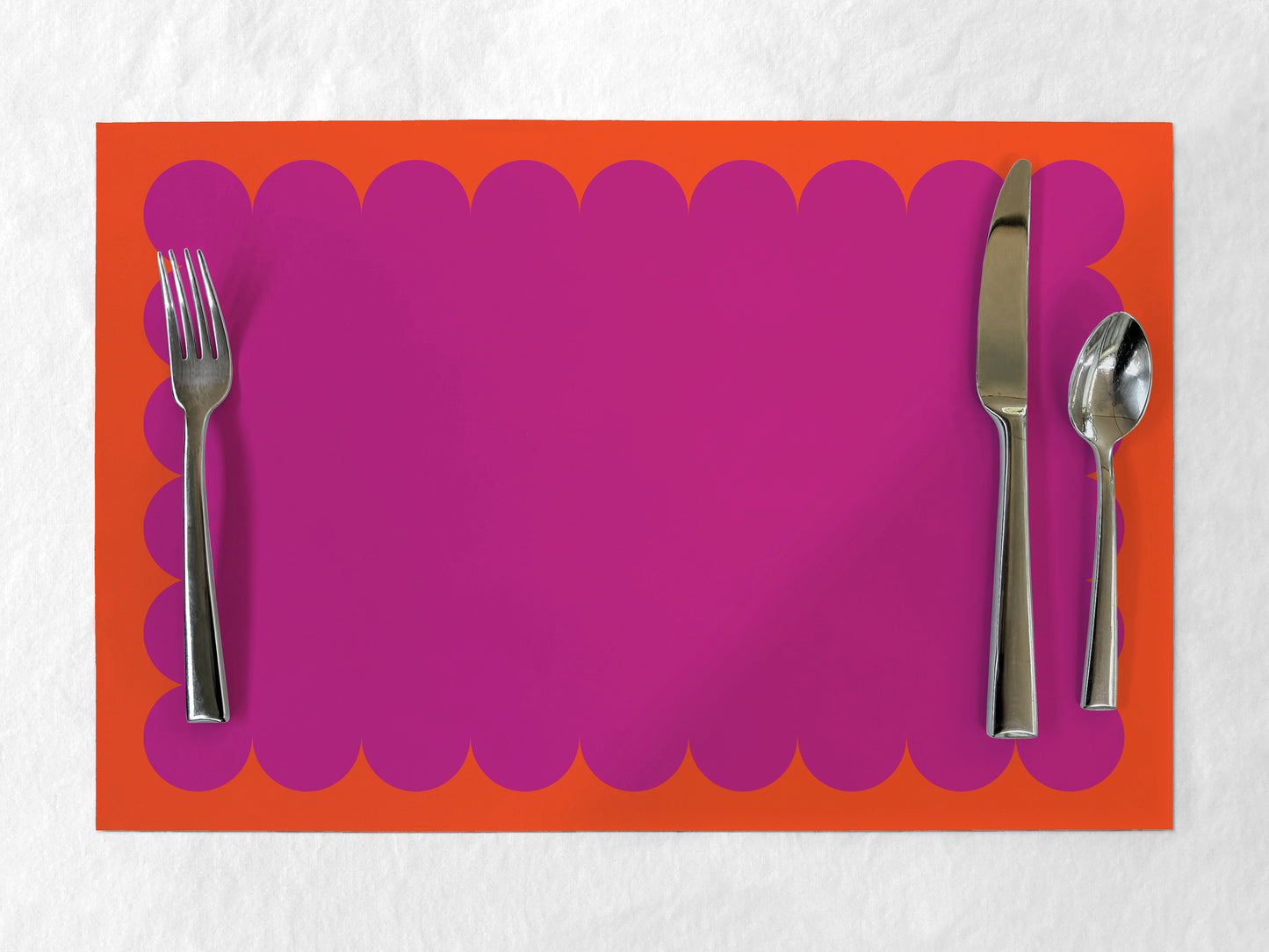 Fuschia paper placemat with scalloped edge on an orange border
