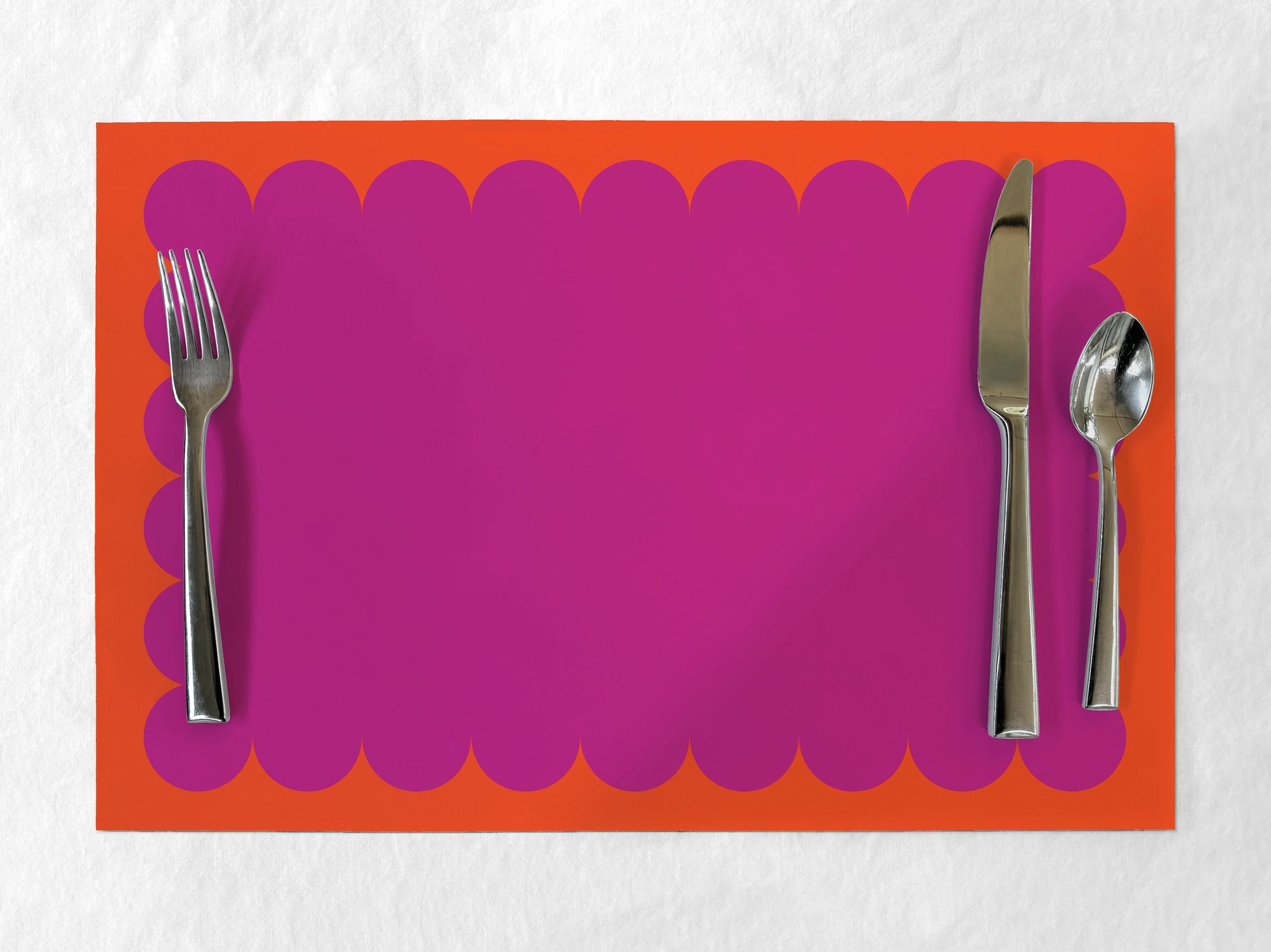 Fuschia paper placemat with scalloped edge on an orange border