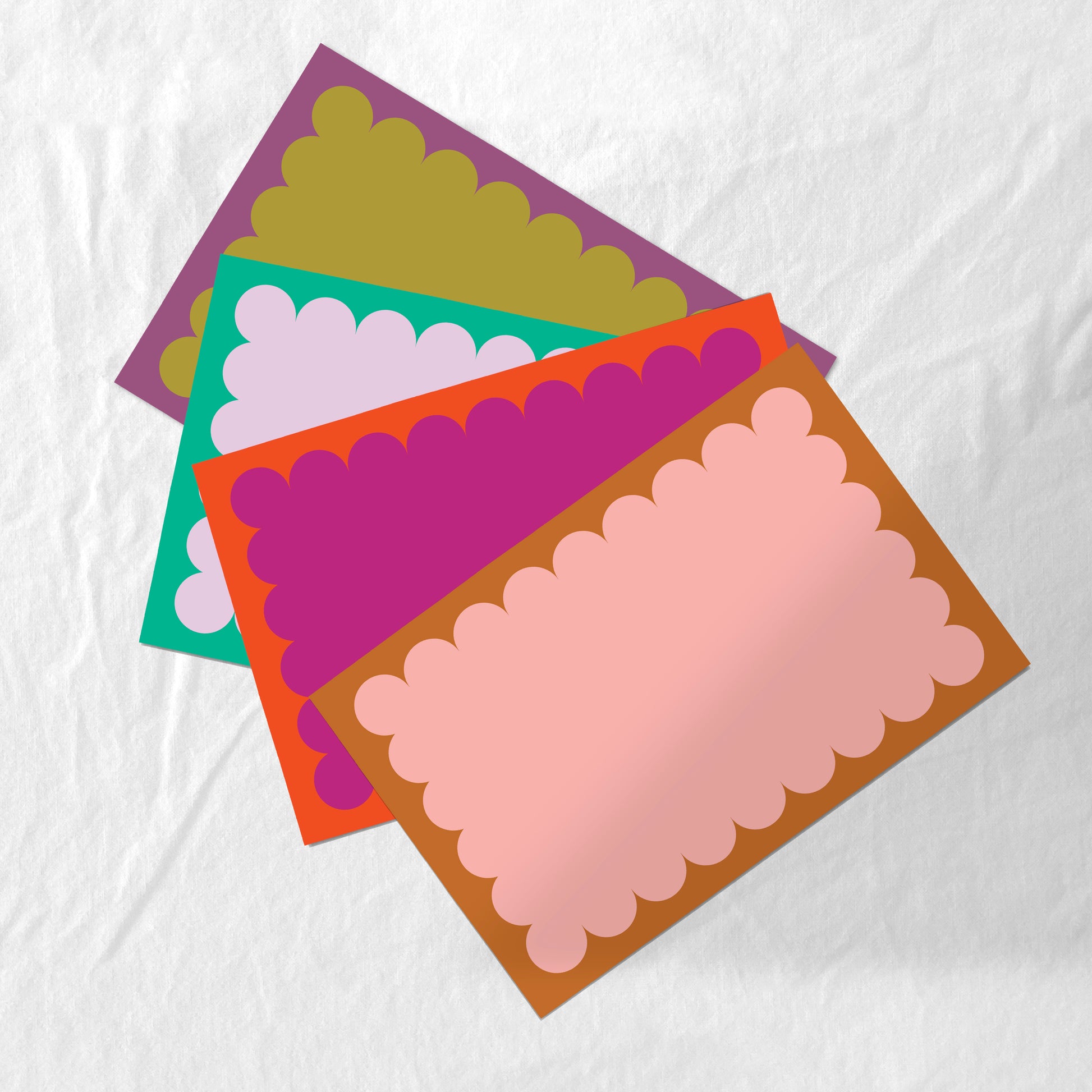 Colorful scalloped-edge paper placemat set on a white fabric background