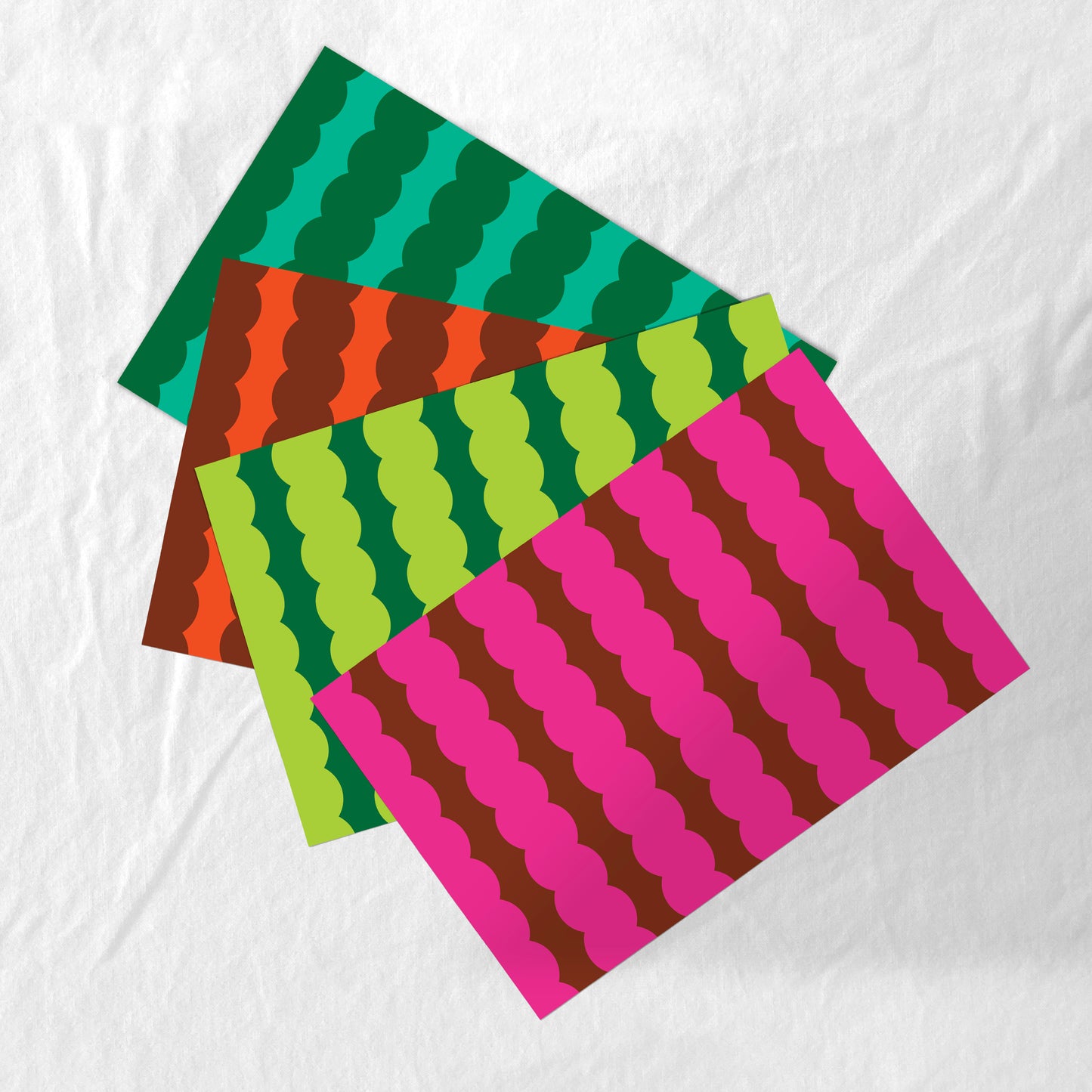 Four colorful patterned paper placemats stacked on a white background