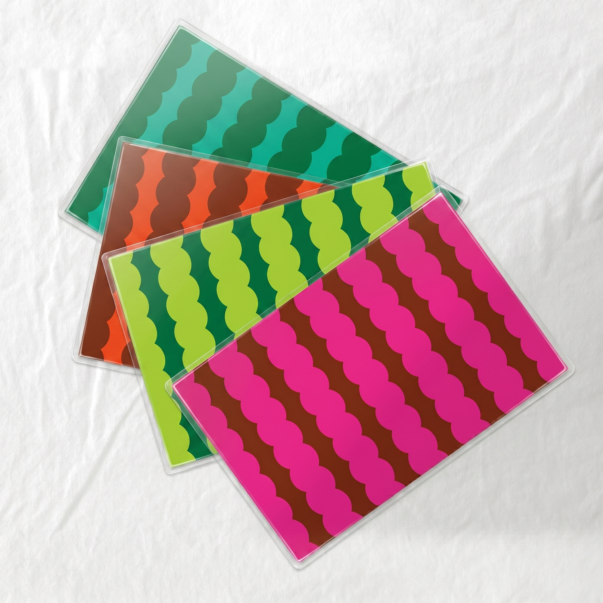 Four laminated colorful patterned paper placemats on a white background