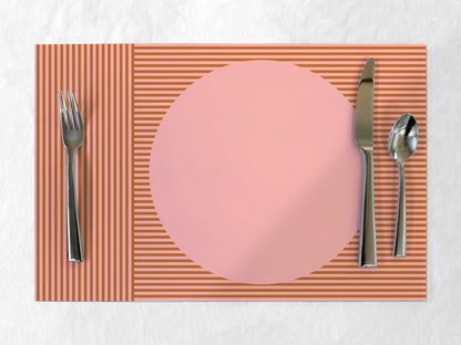 Placemat with pink plate, fork, knife, and spoon on a white background