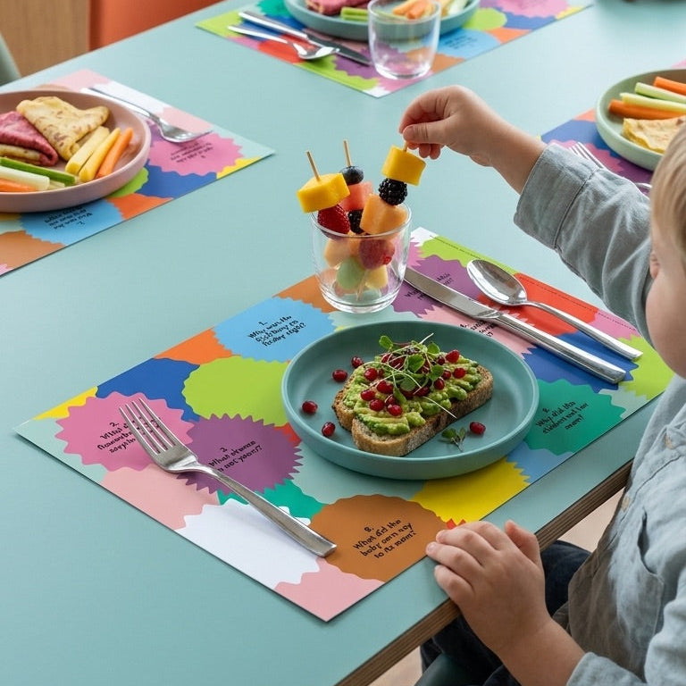 Child sitting at a table with colorful paper placemats, eating a meal.