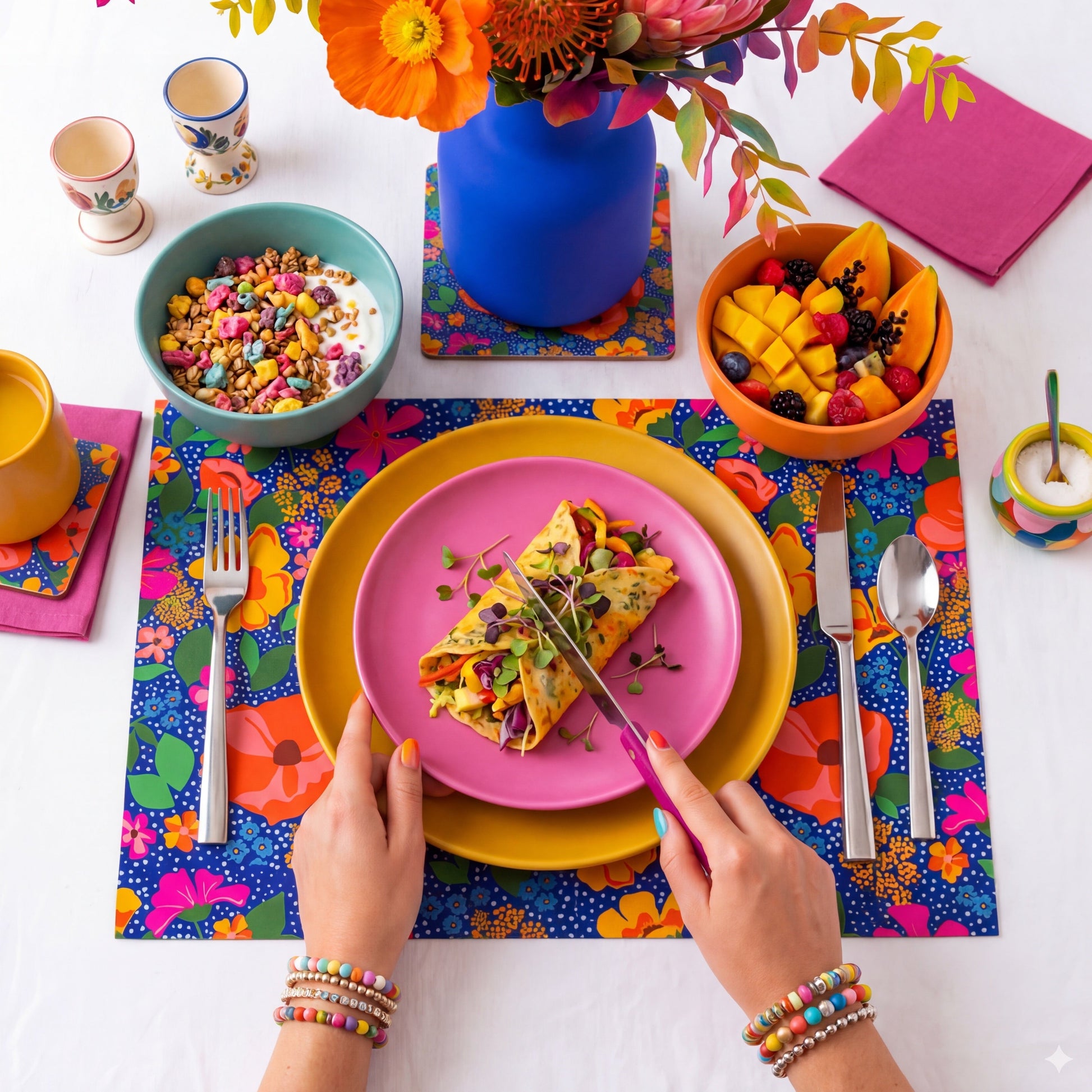 Colorful table setting with a floral arrangement, plates, and colorful floral paper placemat.