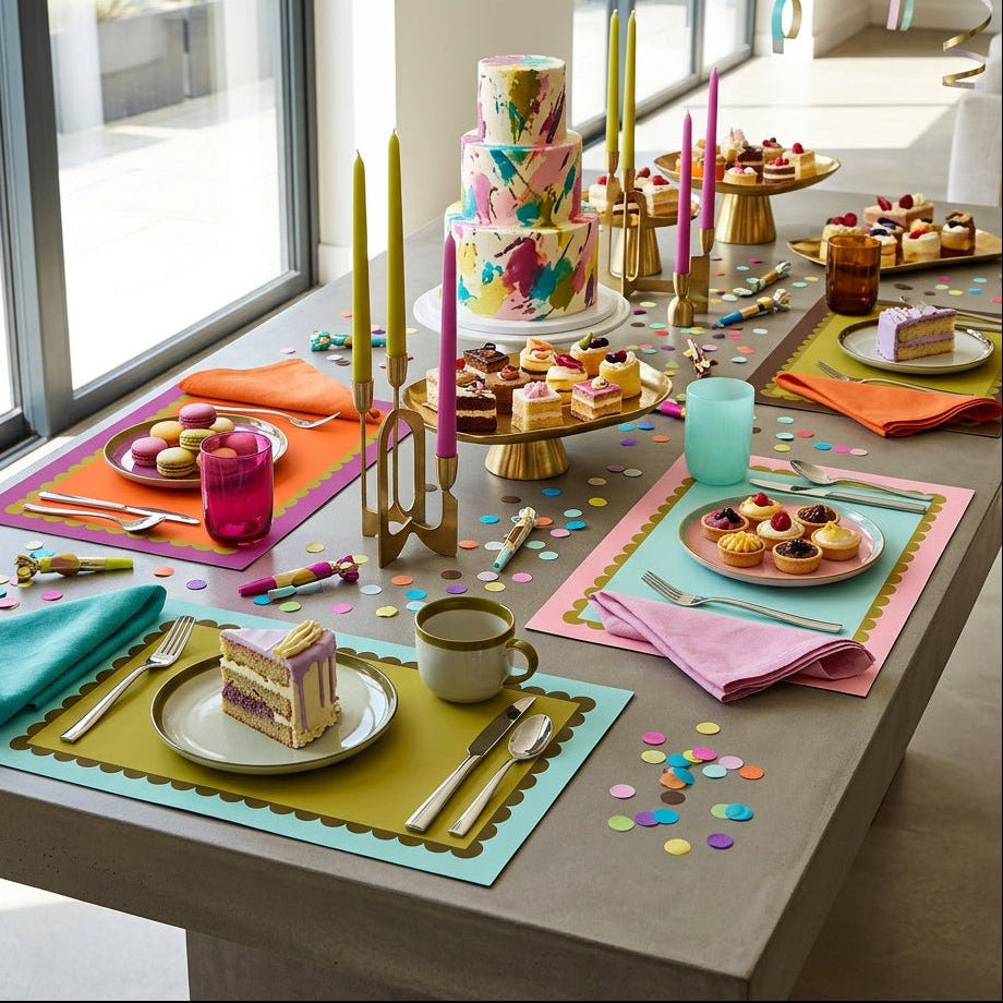 Colorful table setting with a cake, pastries, and colorful scallop framed paper placemats.
