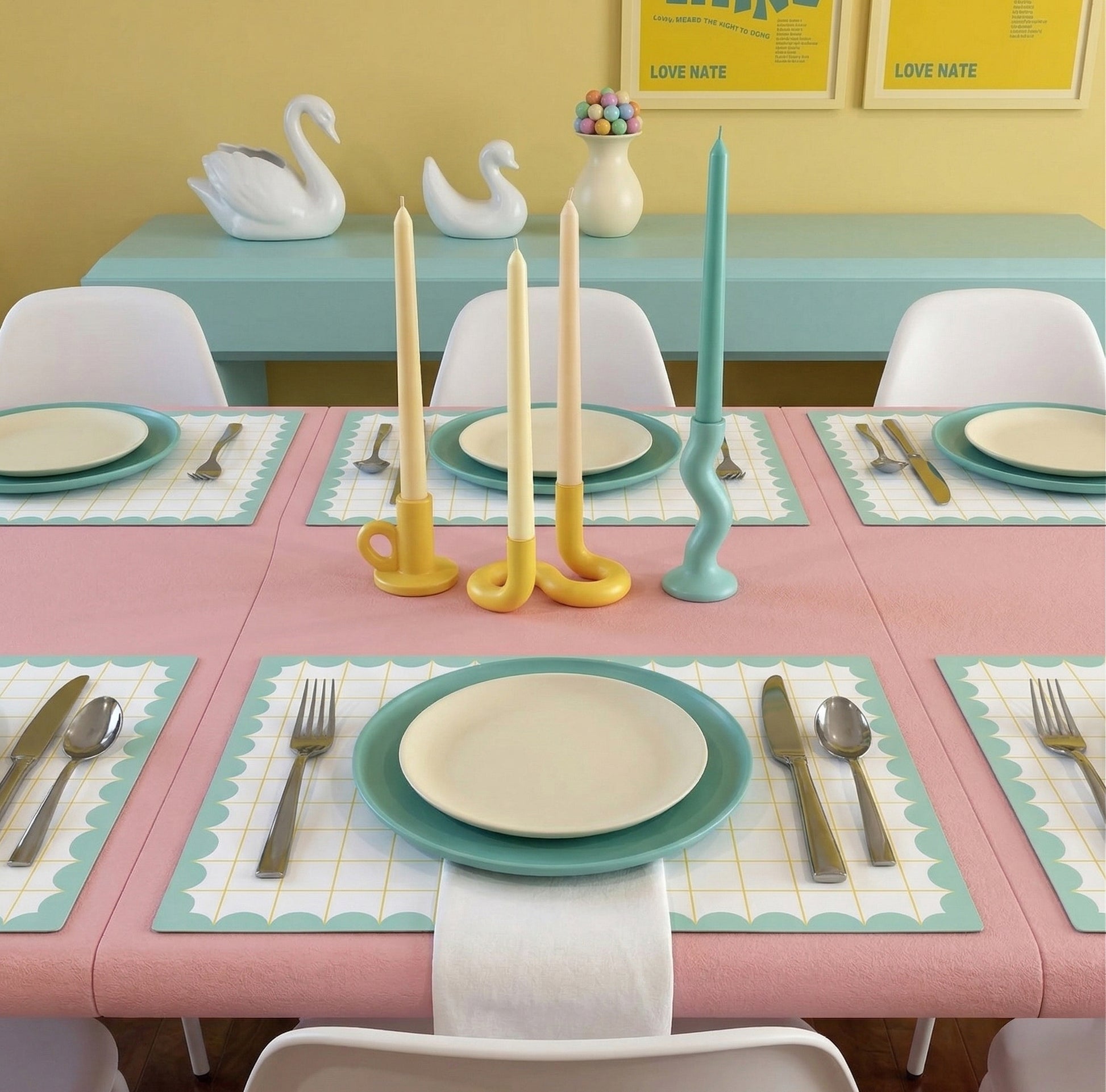 Dining table set with pastel-colored candles and place settings on colorful grid paper placemats.
