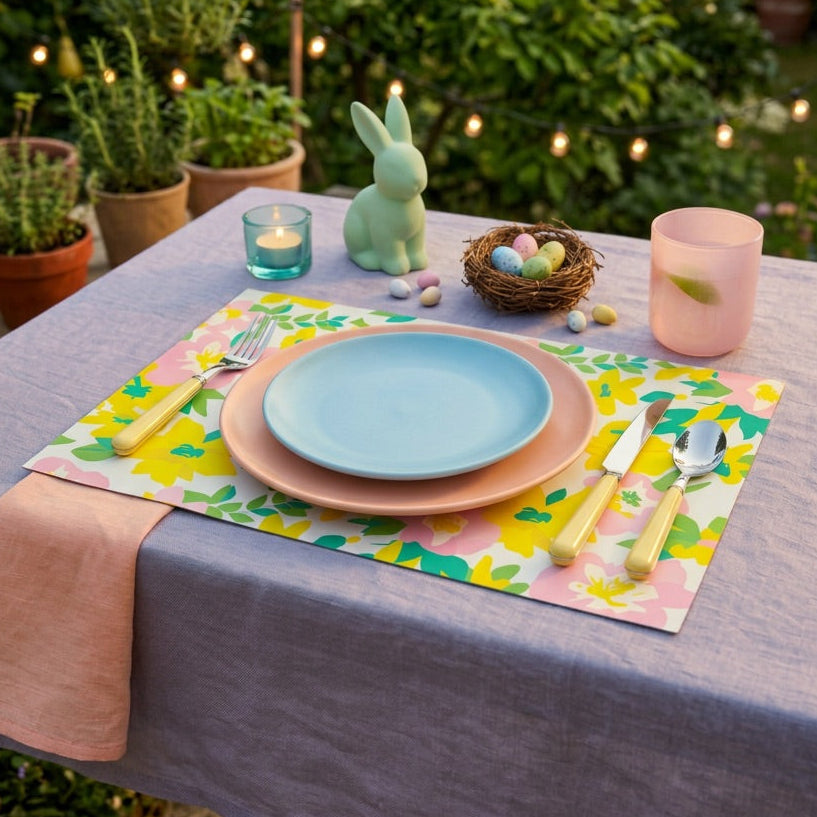 Easter table setting with pastel paper placemats and decorative elements in a garden.