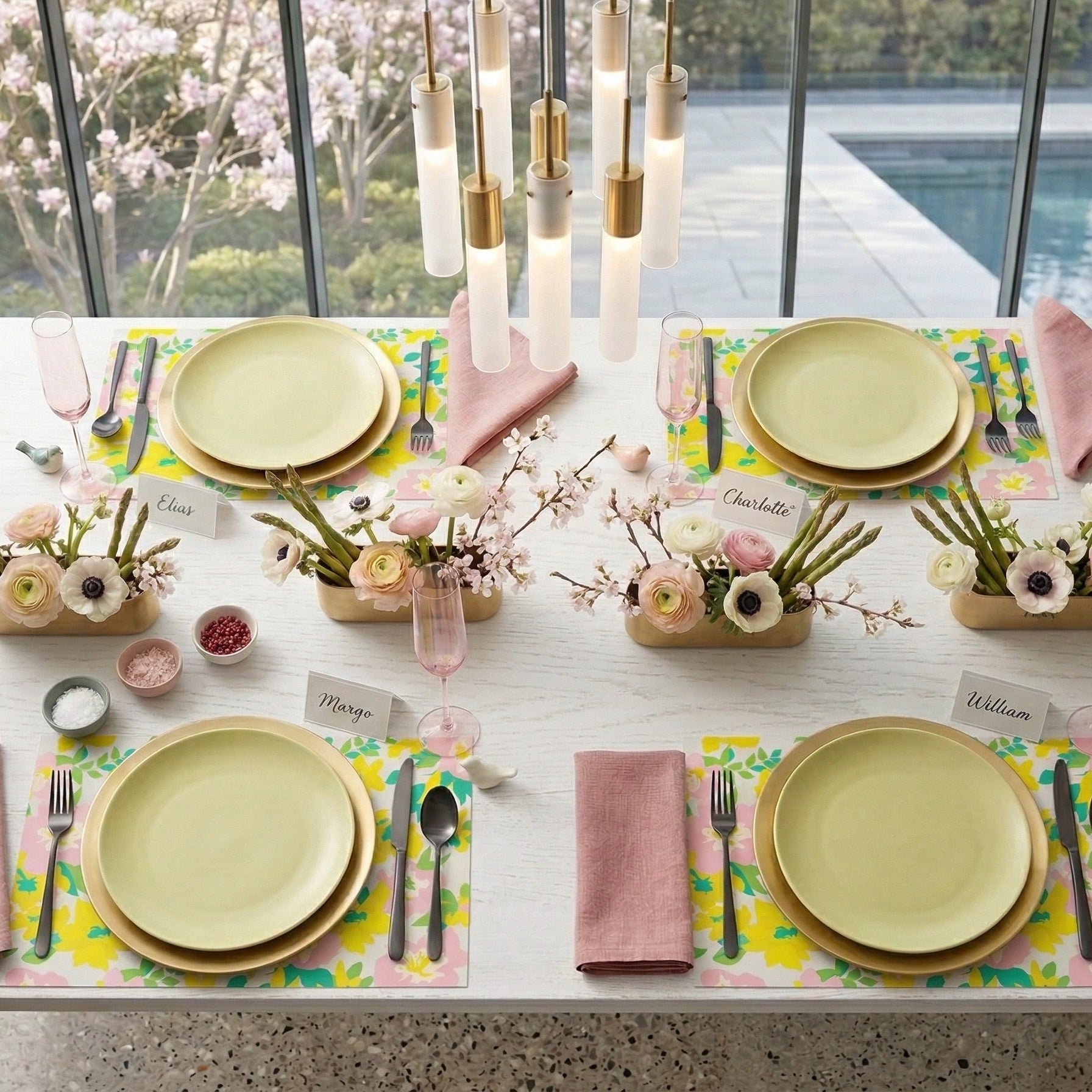 Elegant table setting with yellow plates, pink napkins, and floral paper placemats in a modern indoor setting.