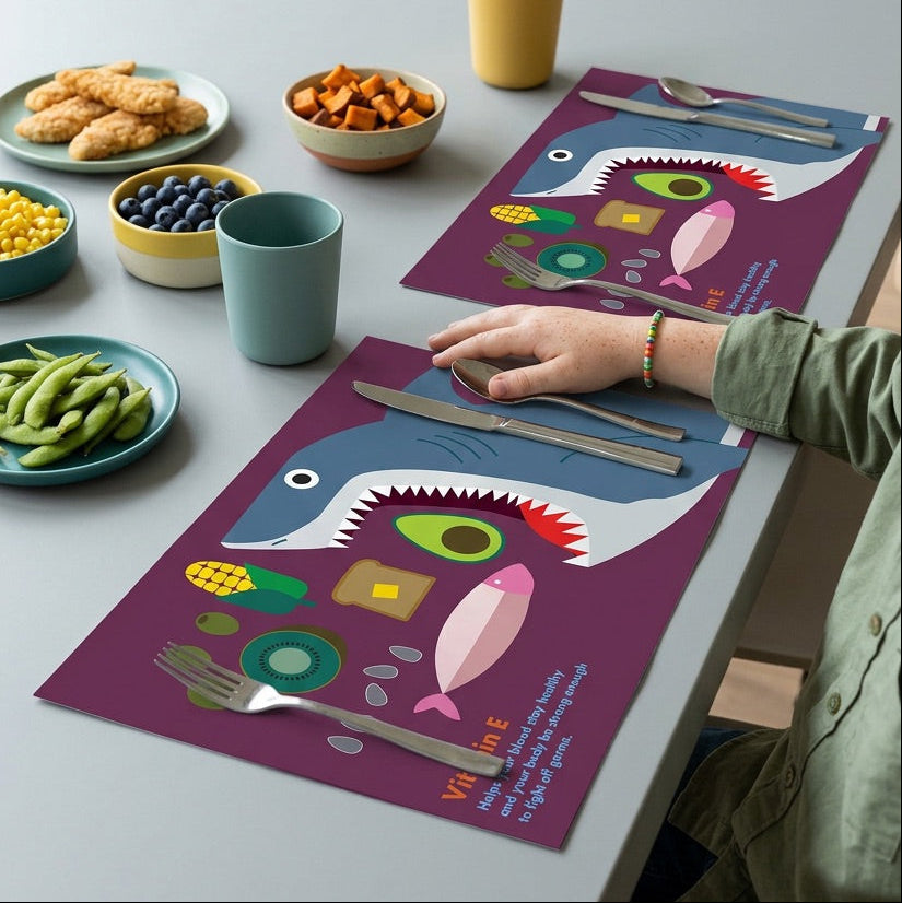 Dining table with colorful paper placemats, food, and a person's hand.